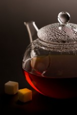 transparent teapot with black tea and sugar